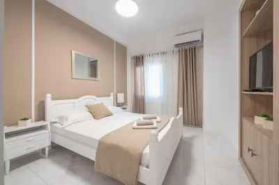 a white bedroom with a white bed and a television at Earthy Green House in Athens