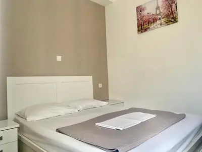 a bedroom with a bed with white sheets and a painting at City Center Athenes rooms in Athens