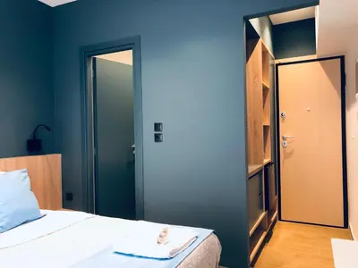 a bedroom with blue walls and a bed with a mirror at Metropolitan Complex room-Faliro in Piraeus