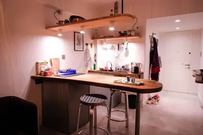 a kitchen with a sink and a counter with two stools at calm and cozy flat with romantic garden in Athens