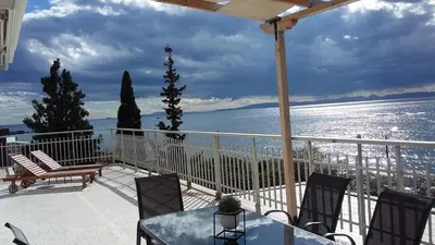 a balcony with a table and chairs and the ocean at Waterfront Penthouse in Saronida
