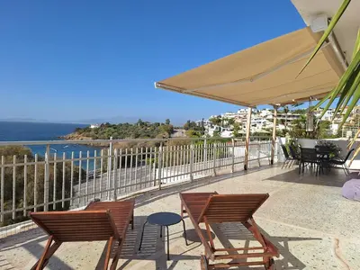 a patio with chairs and tables and an umbrella at Waterfront Penthouse in Saronida