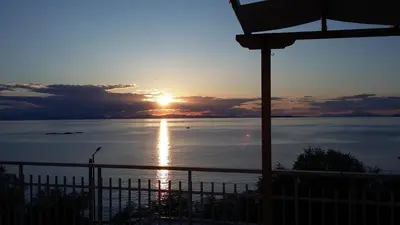 a sunset over the water with the sun setting at Waterfront Penthouse in Saronida