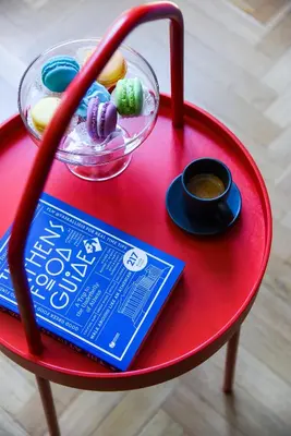 a red table with a plate of food and a drink at CentraL44 WoW CasuaL Suite-Ermou view in Athens