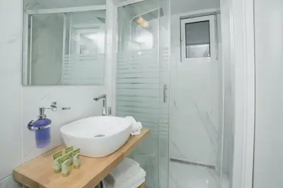 a white bathroom with a sink and a shower at Acropolis Vision in Athens