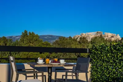 a table and chairs on a balcony with a view of a castle at Acropolis Vision in Athens