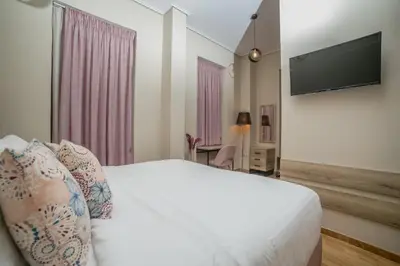a bedroom with a white bed with a flat screen tv at Acropolis Vision in Athens