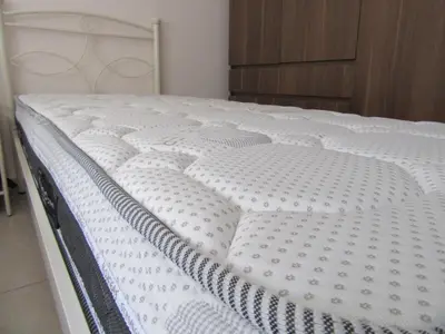 a white bed in a bedroom with a wooden cabinet at ΜΕ ΘΕΑ ΤΟ ΛΙΜΑΝΙ in Piraeus