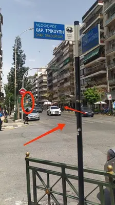 a street sign with a red arrow on a city street at ΜΕ ΘΕΑ ΤΟ ΛΙΜΑΝΙ in Piraeus