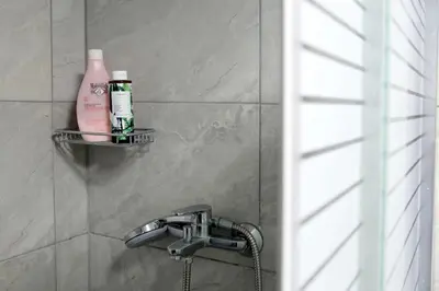 a bathroom with a shower with a soap bottle and a sink at VZ Athens Apartment in Athens