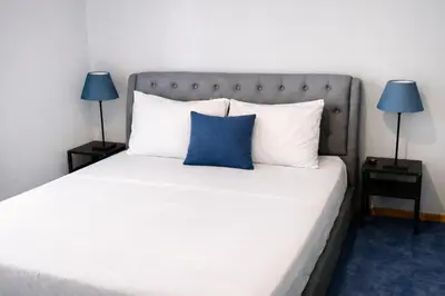 a bed with a blue pillow and two lamps at Comfortable Modern Entire House near the center of Athens-Blue Serenity in Athens