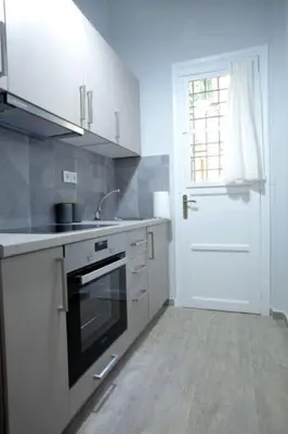 a kitchen with white cabinets and a sink and a door at Super Comfrortable Modern Apartment in Kolonaki in Athens