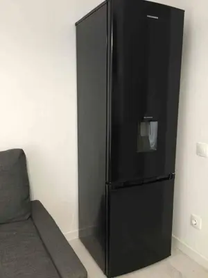 a black refrigerator in a room with a couch at Palio Faliro Deluxe Apartment near the sea in Athens