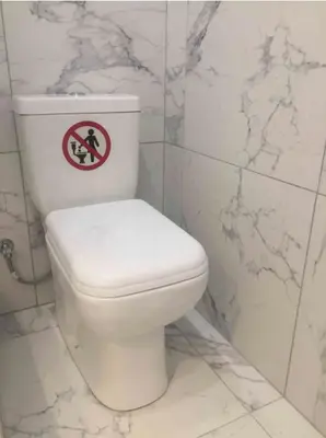 a white toilet in a bathroom with a sign on it at Palio Faliro Deluxe Apartment near the sea in Athens