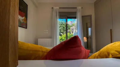 a bedroom with yellow and red pillows and a window at Acropolis Slow Living apt under the Parthenon in Athens