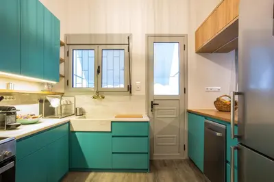 a kitchen with blue cabinets and a door at Acropolis Slow Living apt under the Parthenon in Athens