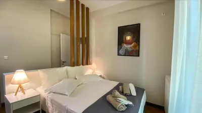 a bedroom with a white bed with a painting on the wall at Acropolis Slow Living apt under the Parthenon in Athens