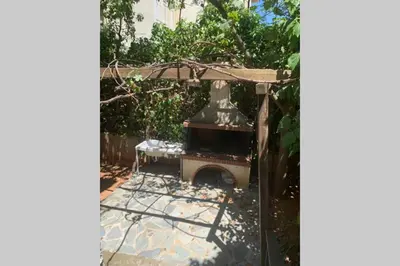 an outdoor fireplace in a yard with trees and a building at Anna's House in Athens