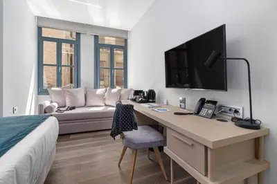 a bedroom with a desk with a television and a couch at Hellenic Vibes Smart Hotel in Athens