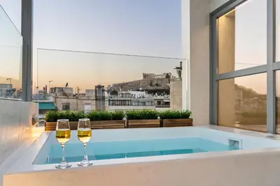 two wine glasses sitting on a bath tub with a view at ACRON suites & apartments in Athens