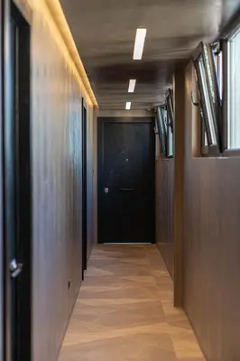 a hallway with a black door and a wooden floor at ACRON suites & apartments in Athens