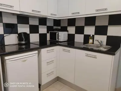 a kitchen with white cabinets and a sink and a microwave at Apartment Maxim in Athens