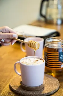 a person pouring honey into a cup of coffee at Eunoia Suite - Monastiraki Square View in Athens