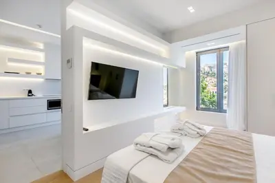 a white bedroom with a flat screen tv on a wall at NS PLACE Modern Apartment Acropolis view in Athens