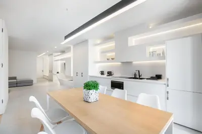 a kitchen and dining room with a wooden table and white chairs at NS PLACE Modern Apartment Acropolis view in Athens