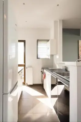 a white kitchen with a sink and a refrigerator at Βright Walled Designed Apt in Glyfada Center 1Gbps in Athens