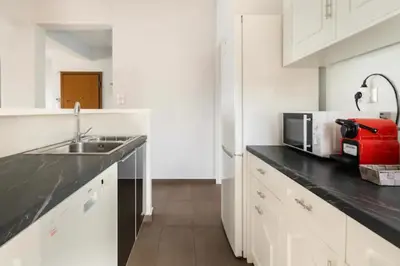a white kitchen with a sink and a microwave at Βright Walled Designed Apt in Glyfada Center 1Gbps in Athens