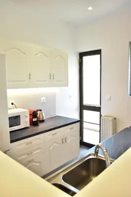 a kitchen with white cabinets and a sink and a microwave at Βright Walled Designed Apt in Glyfada Center 1Gbps in Athens