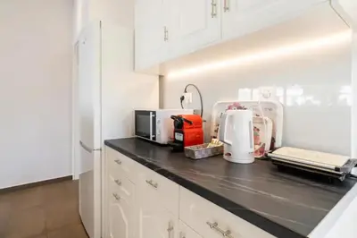 a kitchen with white cabinets and a black counter top at Βright Walled Designed Apt in Glyfada Center 1Gbps in Athens