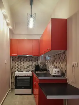a kitchen with red cabinets and a white stove at Stylish Modern Studio in the Heart of Athens in Athens