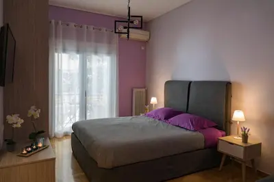 a bedroom with a bed with purple pillows and a window at Stylish Modern Studio in the Heart of Athens in Athens