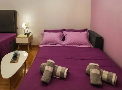 a bedroom with a large bed with purple sheets at Stylish Modern Studio in the Heart of Athens in Athens
