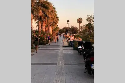 a sidewalk with palm trees and people walking down it at New Modern Apartment - Athens Seaside - 3 Bedrooms in Athens