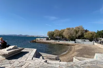 a woman sitting on a bench next to a body of water at New Modern Apartment - Athens Seaside - 3 Bedrooms in Athens