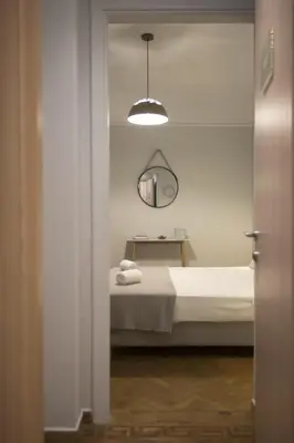 a white bedroom with a bed and a mirror at Apollonos Studio Amalia in Athens
