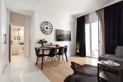a living room with a table and chairs and a clock at Modern Comfort in the Heart of Athens in Athens