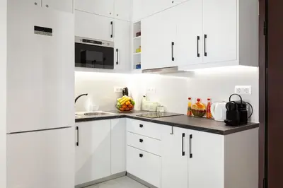 a white kitchen with white cabinets and a sink at Modern Comfort in the Heart of Athens in Athens