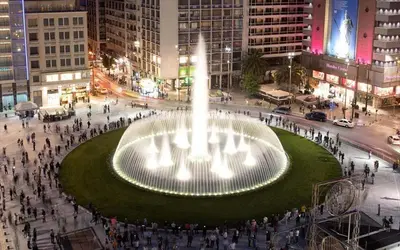 a fountain in the middle of a city at night at Modern Comfort in the Heart of Athens in Athens