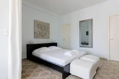 a white bedroom with a large bed and a mirror at Unique Apartment near Acropolis in Athens