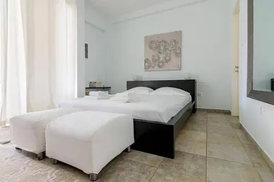 a bedroom with a large bed and two white stools at Unique Apartment near Acropolis in Athens