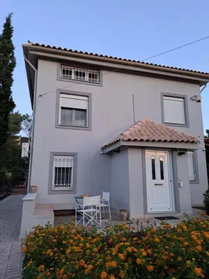a white house with a table and a chair at Studio Katafigi in Anavissos