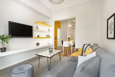 a living room with a couch and a tv on a wall at Bright, Modern Retreat Near Acropolis in Koukaki in Athens