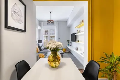 a dining room with a white table and a yellow wall at Bright, Modern Retreat Near Acropolis in Koukaki in Athens