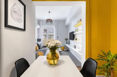 a dining room with a table with a vase of flowers on it at Bright, Modern Retreat Near Acropolis in Koukaki in Athens