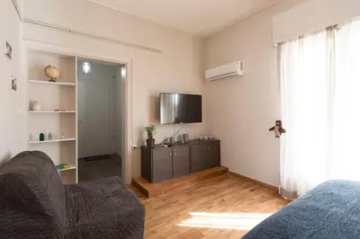 a living room with a tv and a couch and a tv stand at EL GRECO Penthouse in Vibrant Petralona in Athens