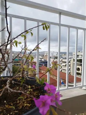a view of a city from a balcony with purple flowers at EL GRECO Penthouse in Vibrant Petralona in Athens